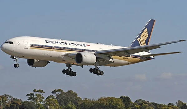 Avião da Singapore Airlines em descentes para aterrissagem, sobrevoando uma área com árvores em um dia nublado, promovendo viagens internacionais e conforto. Singapura e os pontos turísticos.