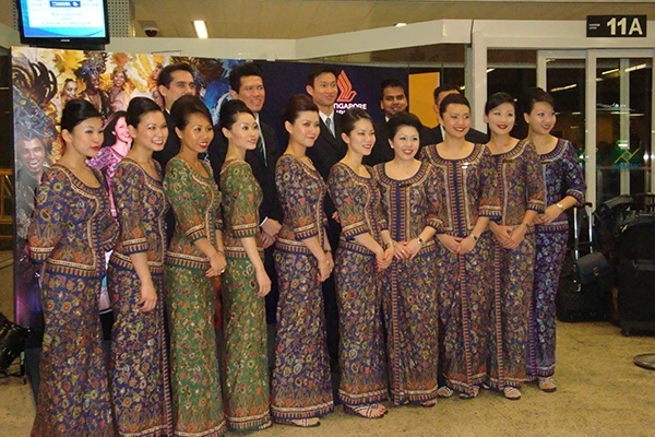 Grupo de comissárias de bordo da Singapura Airlines, com tradicionais vestindo trajes coloridos durante apresentação cultural. Singapura e os pontos turísticos.