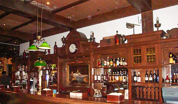 Imagem de um bar clássico com móveis de madeira, várias garrafas de bebidas alcoólicas e decoração vintage em um ambiente aconchegante. Singapura e os pontos turísticos.