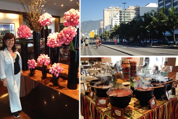 Deusa Rodrigues ao lado de arranjos de flores rosas em um ambiente interno elegante, com uma vista de cidade na janela. Viagens para Ipanema.