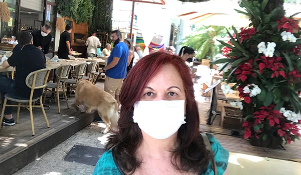 Deusa Rodrigues em ambiente de restaurante ao ar livre, com plantas verdes e decoração colorida ao fundo.