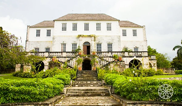 Imagem de uma antiga fazenda colonial bem preservada, com arquitetura clássica, jardins bem cuidados e escadaria de pedra na entrada, representando história e patrimônio brasileiro.
