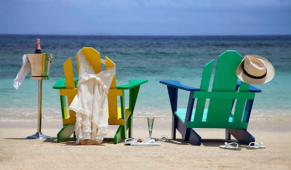Cadeiras de praia coloridas na areia da praia com bebidas e chapéu, ideal para relaxar e aproveitar o verão