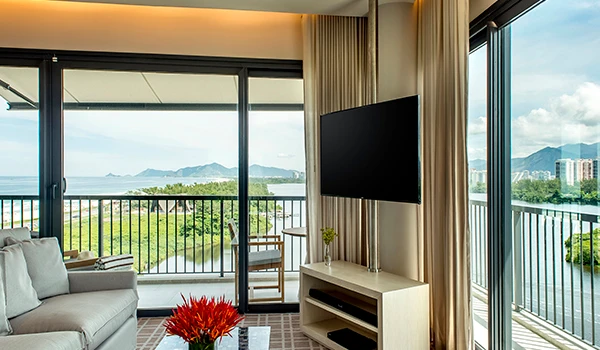 Apartamento do Grand Hyatt com vista panorâmica para a natureza, decorado com móveis modernos e grandes janelas de vidro permitindo bastante luminosidade, ideal para quem busca conforto e contato com a exterior. Uma das atrações sobre o que fazer na Barra da Tijuca.