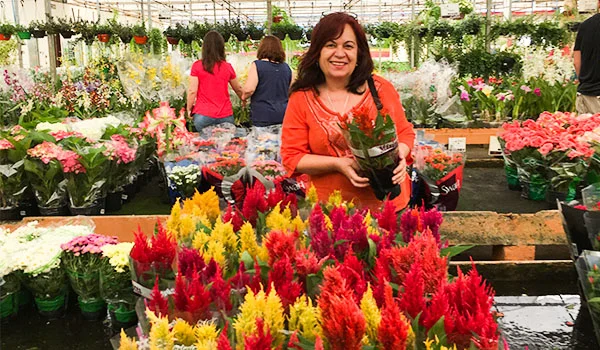 Deusa Rodrigues de blusa laranja segurando um vaso dentro de um dos shopping de flores em Holambra.