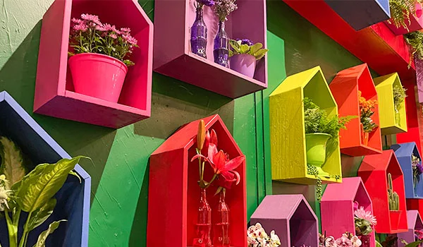 Foto de uma parede com vários vasos entre casinhas coloridas, na Flores de Holambra na Expoflora.
