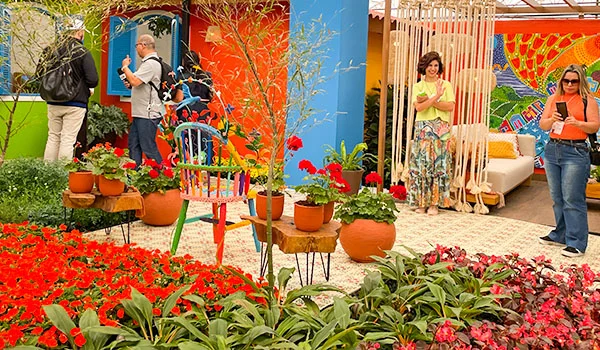 Foto da mostra de paisagismo de Flores de Holambra na Expoflora, onde se observar pessoas visitantes e objetos de jardim.