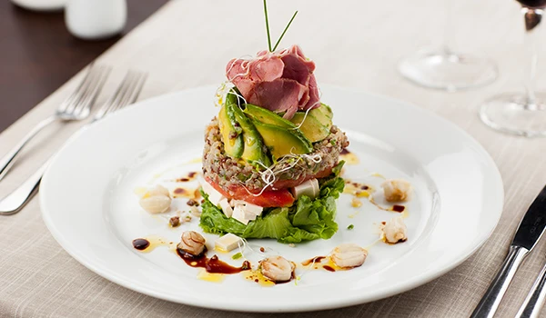 Prato gourmet com carne, vegetais e molho delicado, preparado com técnica de alta gastronomia, apresentado em prato clássico de jantar elegante.