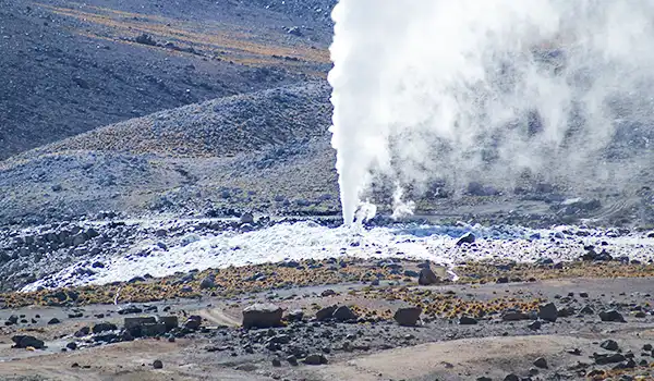Erupção vulcânica ativa com fumaça e lava em ambiente natural, cenário de atividade geotérmica com destaque para a paisagem de vulcão em erupção.