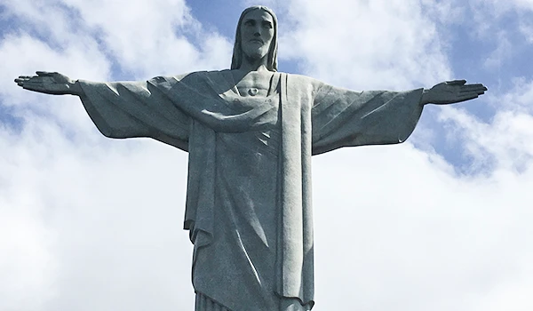 Imagem da famosa estátua do Cristo Redentor no Rio de Janeiro, uma das maiores atrações turísticas do Brasil, com céu parcialmente nublado ao fundo.
