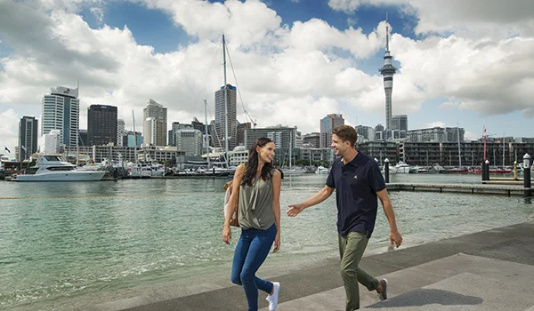 Foto de um casal andando em uma calçada da beira do pier em Auckland, na Lua de Mel na Nova Zelândia.