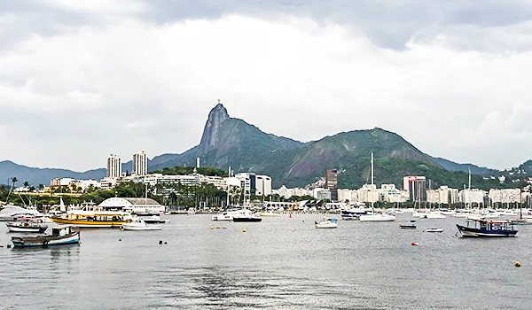 Visualização do horizonte de Rio de Janeiro com vista para o Cristo Redentor no topo do Corcovado, incluindo vários barcos no mar durante o dia.