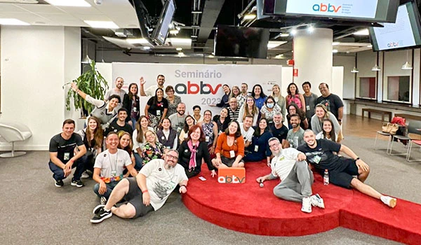 Grupo de participantes no seminário abbv 2023 posando para foto em ambiente corporativo, com mais de 30 pessoas sorrindo e mostrando entusiasmo na palestra.