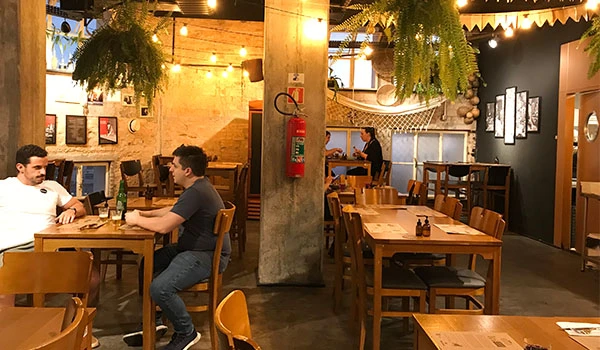 Interior de restaurante alegre com iluminação aconchegante, decoração moderna e clientes desfrutando de suas refeições, criando ambiente acolhedor para happy hour.