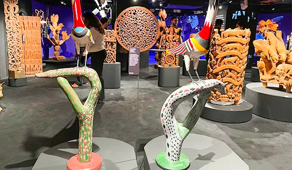 Exposição de esculturas de crocodilos coloridos em um museu de arte contemporânea, com diversas obras artísticas ao fundo.