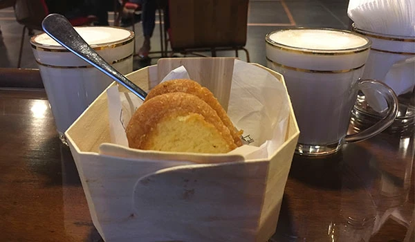 Pão com duas xícaras de café com leite, ideal para café da manhã ou lanche, em ambiente aconchegante.