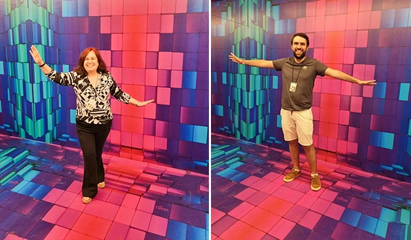 Deusa Rodrigues e seu assessor e empolgada posando diante de uma parede e piso coloridos em um ambiente moderno, ideal para fotos e experiências visuais impactantes.