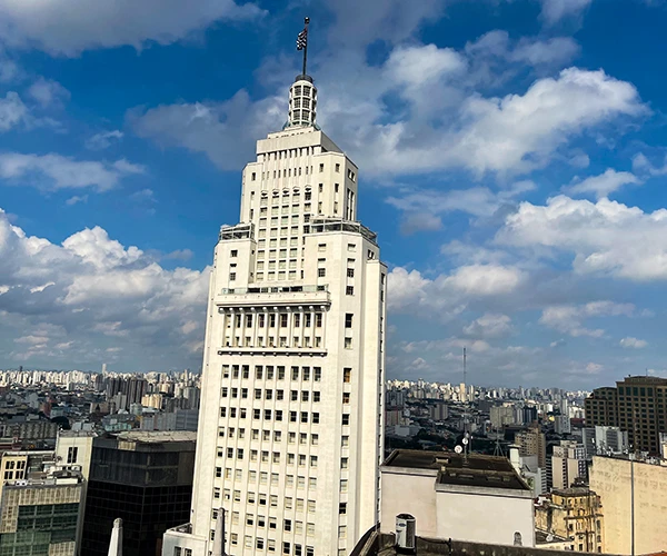 Imagem do Edifício Martinelli, um marco arquitetônico em São Paulo, destacando sua estrutura imponente contra o céu com nuvens, representando um ícone empresarial e cultural.