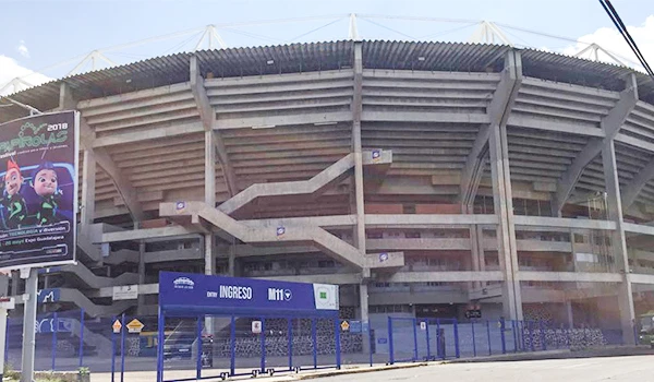 Estádio com entrada principal sinalizada por cartaz de acesso, localizado preparado para evento de grande porte.
