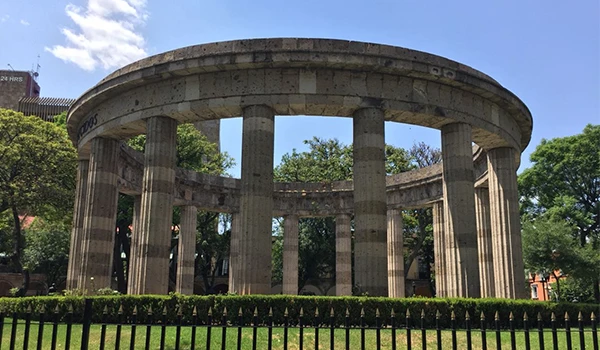 Imagem do Monumento de Guadalajara, com colunas clássicas, localizado em um parque verde sob céu azul.