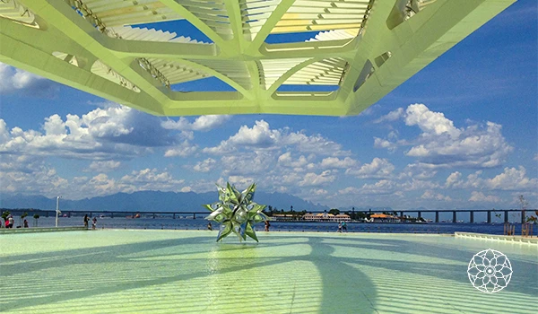 Estrutura moderna de um parque com vista para céu aberto, nuvens e uma ponte ao fundo, com uma decoração de estrelas na área central.