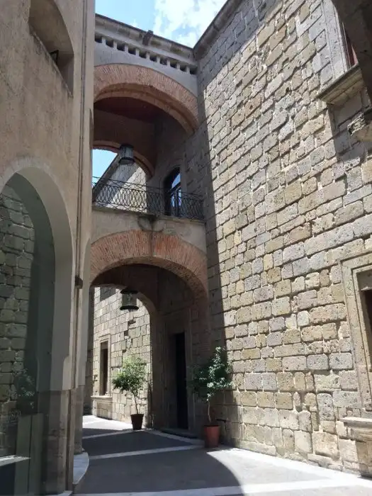 Imagem de uma fachada de edifício histórico com paredes de pedra, arcos e janelas de estilo clássico no centro de uma cidade charmosa, com detalhes arquitetônicos que destacam a beleza da construção. O que fazer em Guadalajara.