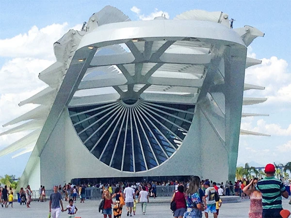 Imagem do Museu do Amanhã , um edifício moderno de arquitetura inovadora, com uma grande estrutura curvada e visitantes ao redor. Cultura no Rio de Janeiro.