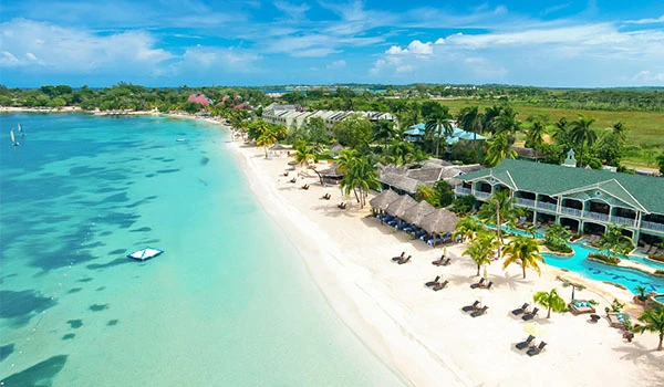 Visual deslumbrante de uma praia paradisíaca com areia branca, águas cristalinas e cabanas de palha, ideal para férias relaxantes em um destino tropical.