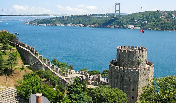 Vista do estreito de Bósforo, em Istambul, na Turquia, com a Fortaleza de Rumeli Hisarı em primeiro plano e a Ponte do Bósforo ao fundo, ligando a Europa à Ásia.