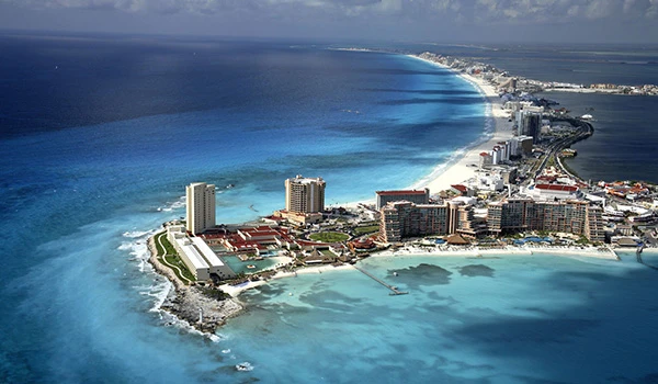 Vista aérea de Cancun, um destino turístico famoso no México, mostrando suas águas azul-turquesa, praias de areia branca e hotéis de luxo ao longo da orla.
