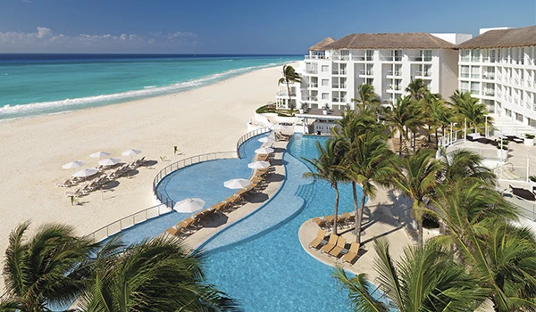 Imagem de resort com piscina ao ar livre, praias de areia branca e mar azul ao fundo, rodeado por palmeiras, ideal para férias de descanso na praia.