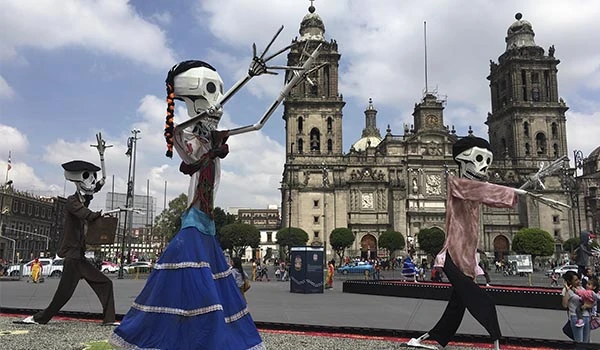 Dança de esqueletos grandes e coloridos no centro histórico com a catedral ao fundo, uma celebração cultural tradicional brasileira cheia de cores e movimento.