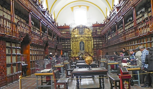 Fotos da biblioteca antiga com estantes de madeira e cadeiras em um ambiente histórico e elegante na Viagem para Puebla.