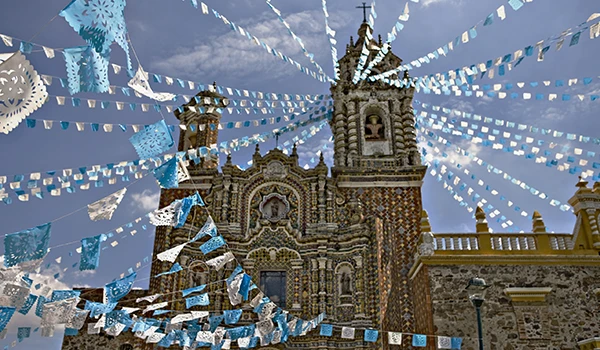 Fachada de uma igreja antiga decorada com bandeirinhas coloridas em homenagem às festas tradicionais, criando um clima festivo e religioso.