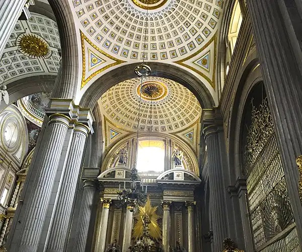 Interior de uma igreja com arquitetura clássica, destaque para o teto decorado em ouro e detalhes ornamentais dourados, colunas imponentes na Viagem para Puebla.