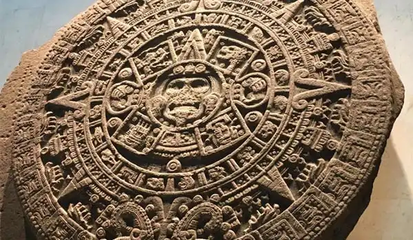 Imagem de um calendário asteca antigo, detalhado e com inscrições indígenas, representando a cultura ancestral mexicana.