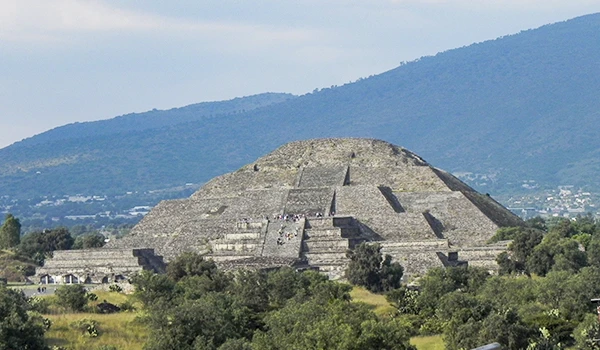 Imagem das Pirâmides do Sol e da Lua em contraste com montanhas e céu azul.