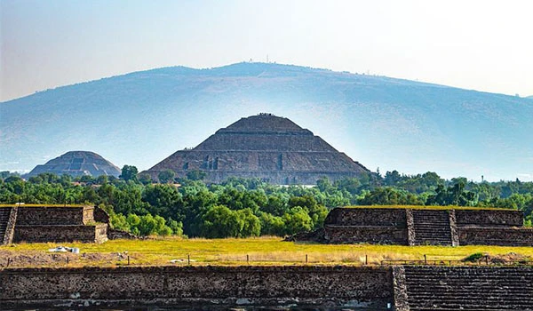 Foto das Pirâmides do Sol e da Lua no México, cercada de natureza.