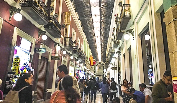 Imagem de uma movimentada galeria ou shopping center com várias pessoas passeando, lojas e decoração charmosa, na Viagem para Puebla.