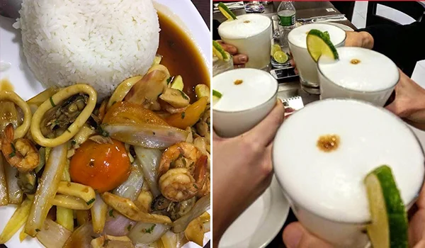 Prato de frutos do mar com arroz branco, acompanhado de lula, camarões, cebola, pimentão e tomate. Ao lado, várias pessoas brindam com taças de uma bebida branca espumosa, decoradas com fatias de limão.