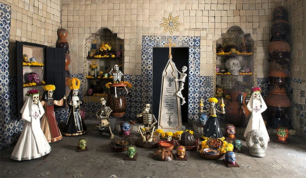 Cemitério de bonecas decorado com flores, velas e elementos tradicionais mexicanos, representando celebração do Dia dos Mortos no México com detalhes coloridos e símbolos culturais, na Viagem para Puebla.