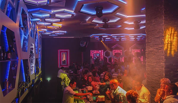 Imagem de uma casa noturna vibrante com iluminação colorida, espaço movimentado e pessoas se divertindo ao som de música ambiente, ideal para festas. Lua de Mel em Cancun.