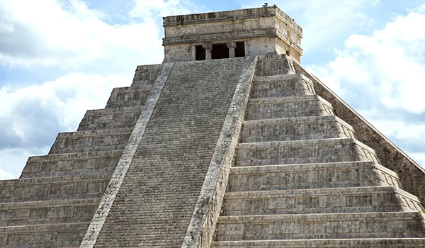 Imagem da pirâmide de Chichen Itza, uma das Sete Maravilhas do Mundo, localizada na Península de Yucatán, no México, com detalhes de sua estrutura de pedra e escadarias imponentes na Lua de Mel em Cancun.