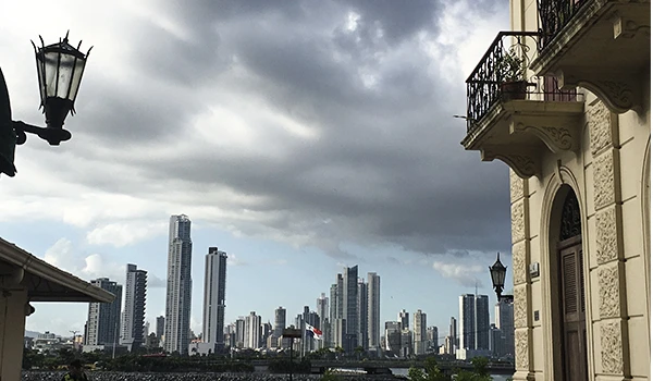 Imagem de uma paisagem urbana em um dia nublado, com arranha-céus modernos ao fundo e prédios antigos na frente, com vista para o horizonte de uma cidade grande, sob céu parcialmente coberto por nuvens.