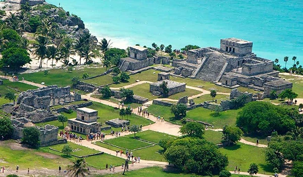 Foto de Tulum com suas pirâmides e estruturas de pedra situadas em uma área verdejante perto do mar na Lua de Mel em Cancun.