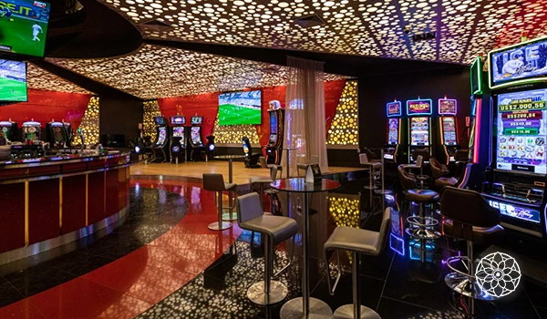 Interior de um cassino com máquinas de jogos e telas de apostas, iluminação colorida e ambiente animado para jogos de azar e entretenimento.