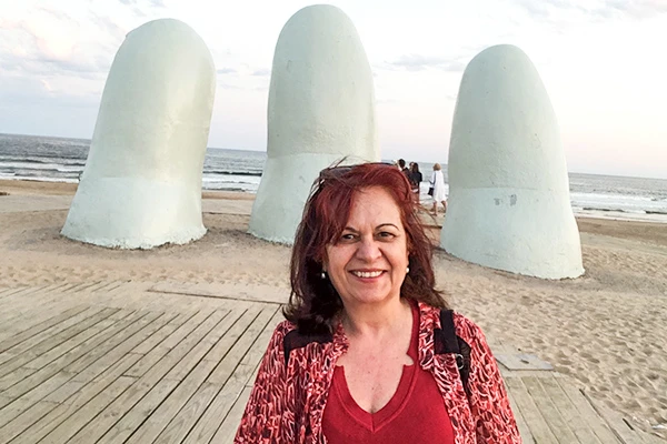 Deusa Rodrigues na praia ao lado das esculturas dos dedos com céu nublado ao fundo. Ideal para quem busca pontos turísticos culturais e atividades. Cassino Punta del Este.
