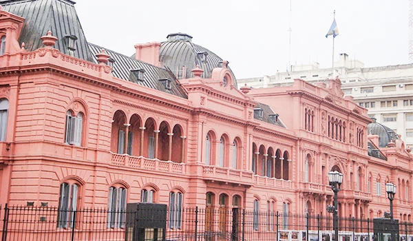 Imagem do Palácio do Governo, Casa Rosada, na Argentina, exibe uma estrutura imponente e bem preservada, com detalhes arquitetônicos históricos e janelas elegantes, destacando-se pela cor rosa vibrante e elementos clássicos do estilo europeu. Viagem para Buenos Aires.