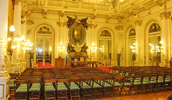 Salão do palácio em estilo clássico e barroco, com poltronas de madeira e iluminação elegante, ideal para eventos culturais e apresentações artísticas. Viagem para Buenos Aires.