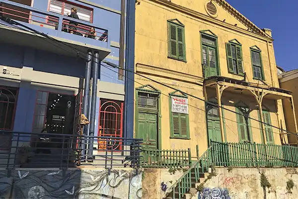 Imagem de edifícios históricos com arquitetura colonial colorida, janelas verdes e varandas, representando o charme do centro antigo de Valparaiso no Chile.